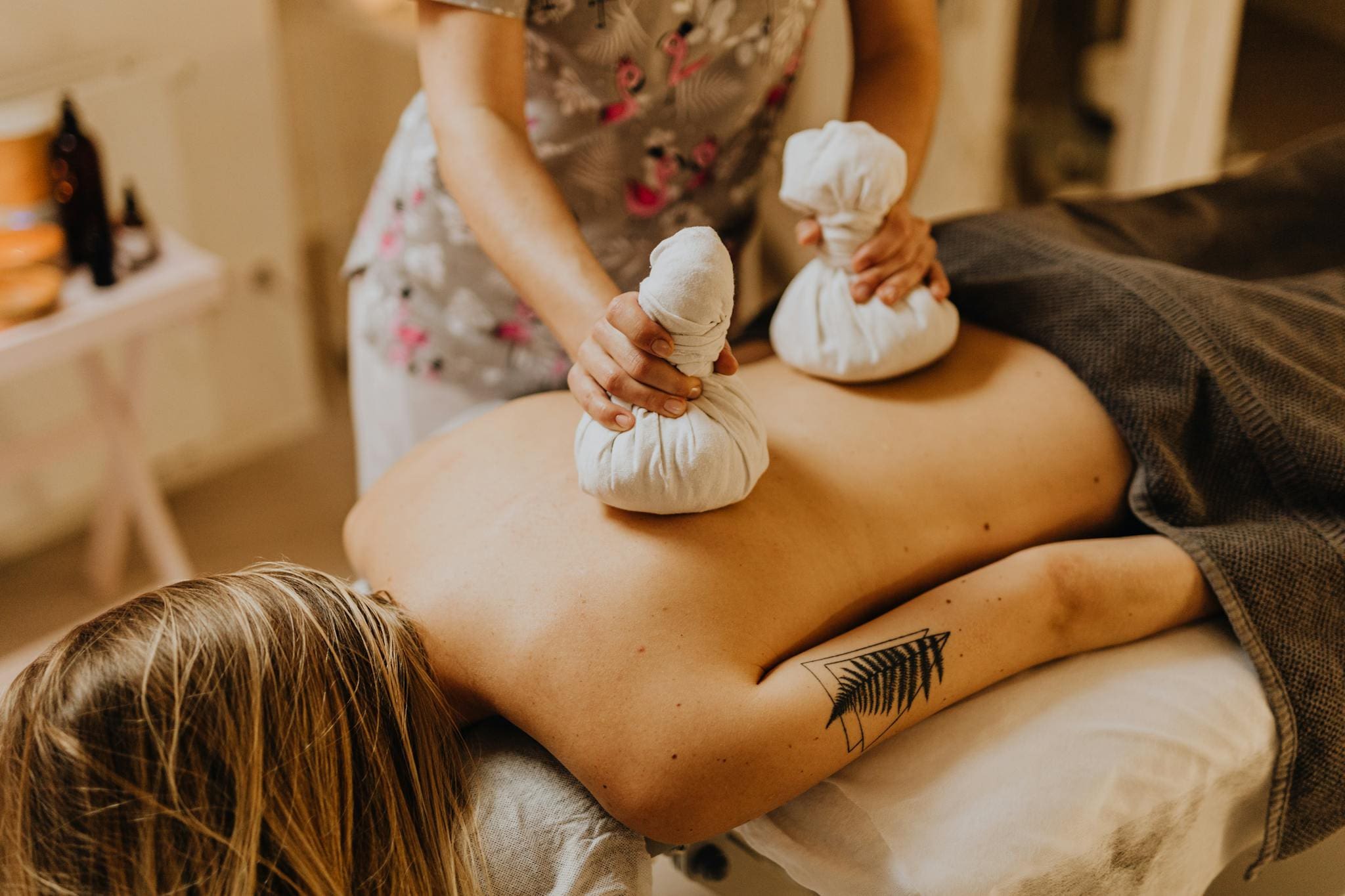 A woman enjoys a traditional herbal compress massage for relaxation and wellbeing.